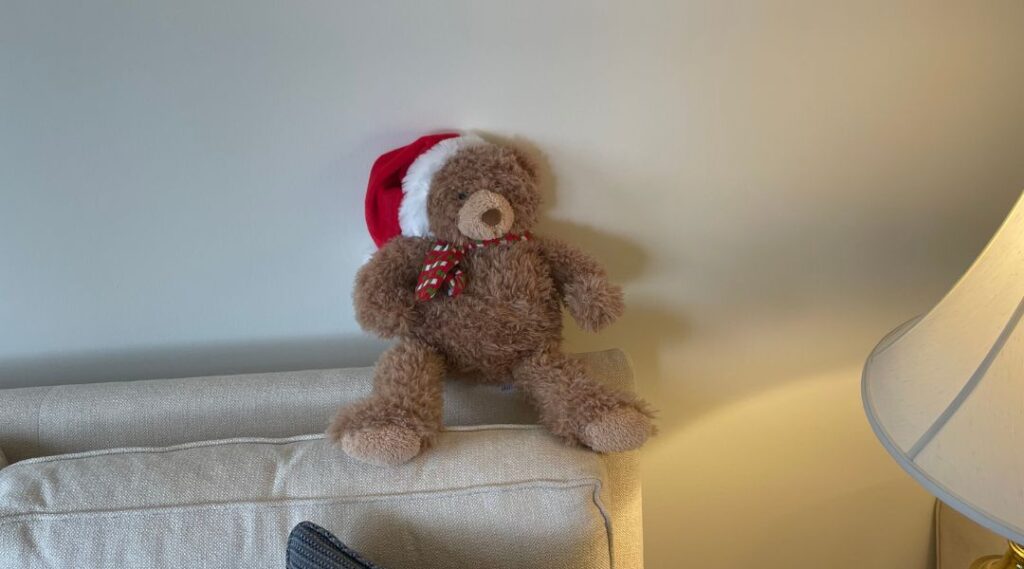 Cute teddy bear sitting upright on couch