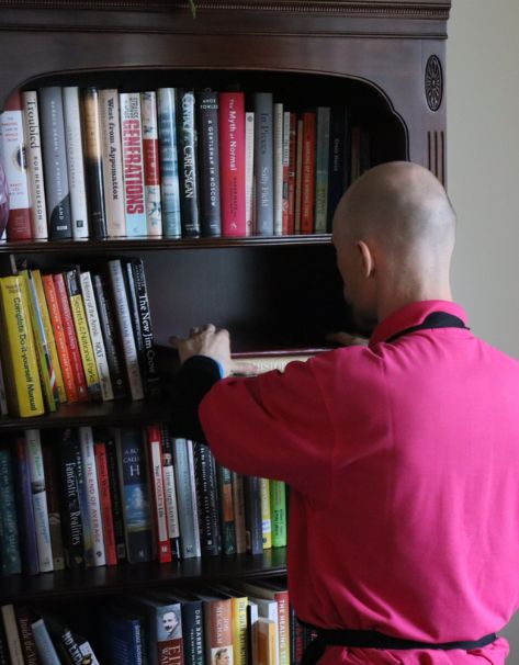 Roses daughters move manger carefully organizing books on a bookshelf