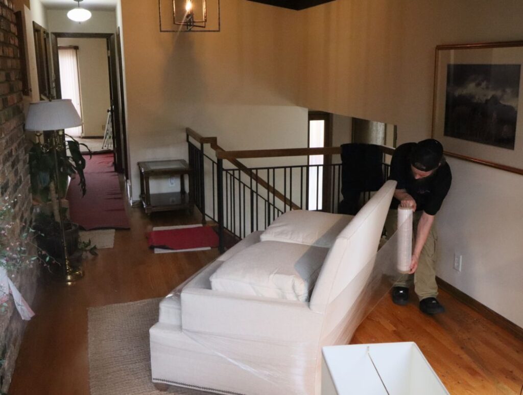 Roses daughters moving shringwrapping a couch before loading it onto moving truck